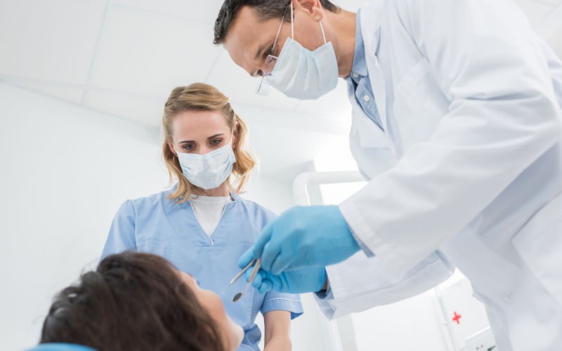Dentist and its associate working with a client 